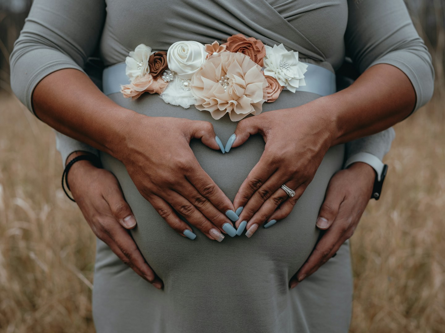 Hands resting on an expectant parent’s abdomen